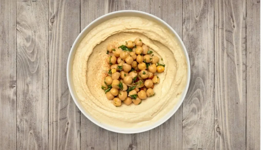 What is hummus — creamy chickpea and tahini dip served at Aladdin Mediterranean Cuisine in Houston, topped with olive oil and paprika.