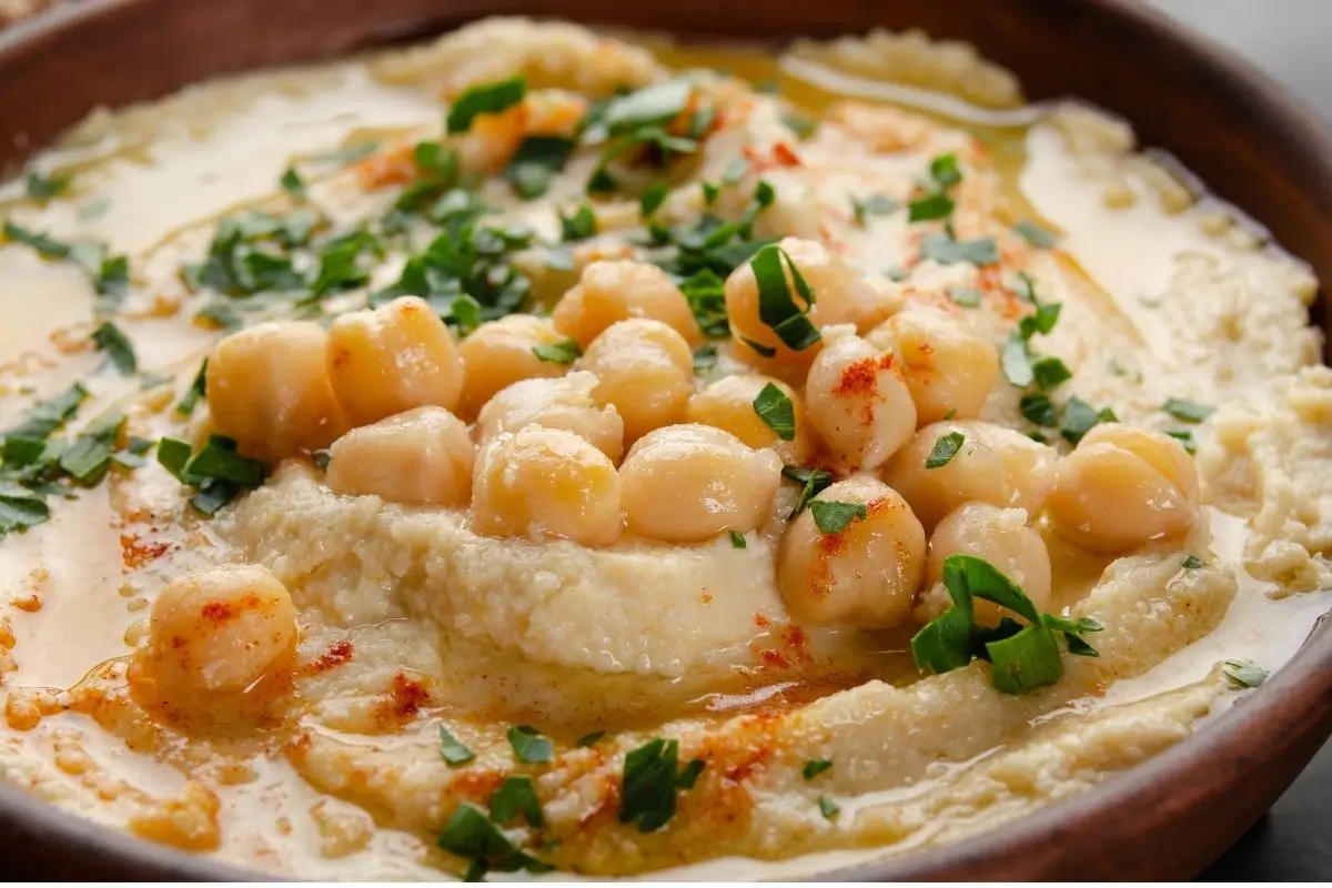 Homemade hummus served in a rustic bowl, drizzled with extra‑virgin olive oil and sprinkled with paprika and fresh parsley.