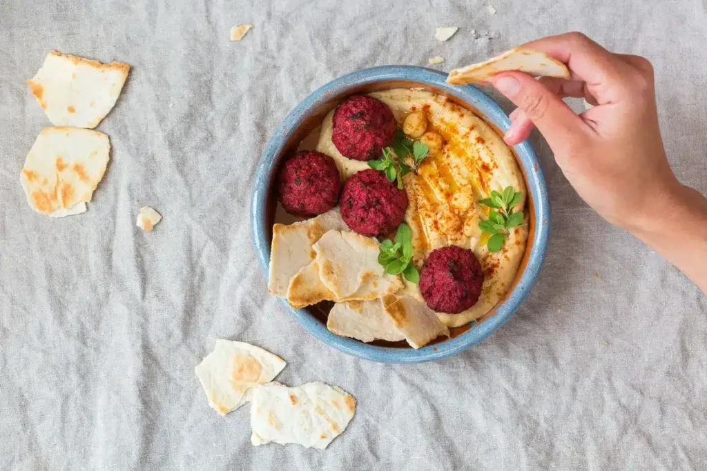 Vibrant beet falafel served on creamy hummus with pita bread, ideal for vegan Mediterranean recipes