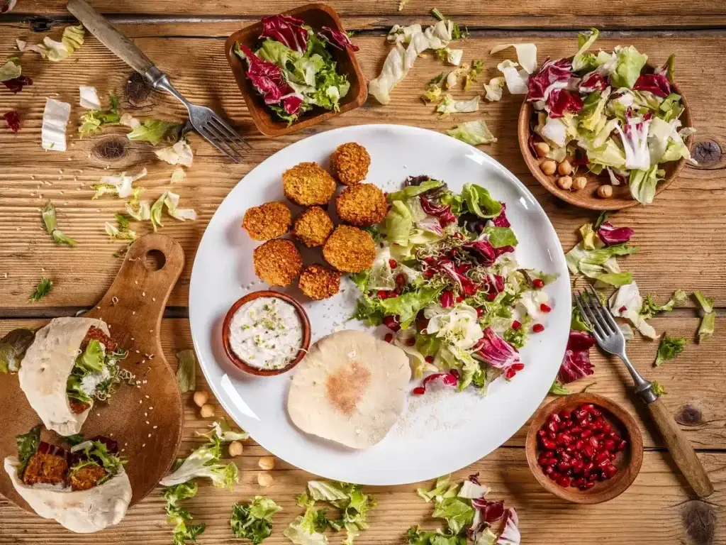 Plate of crispy falafel patties with fresh salad, tahini sauce, and pita bread, perfect for vegan Mediterranean recipe