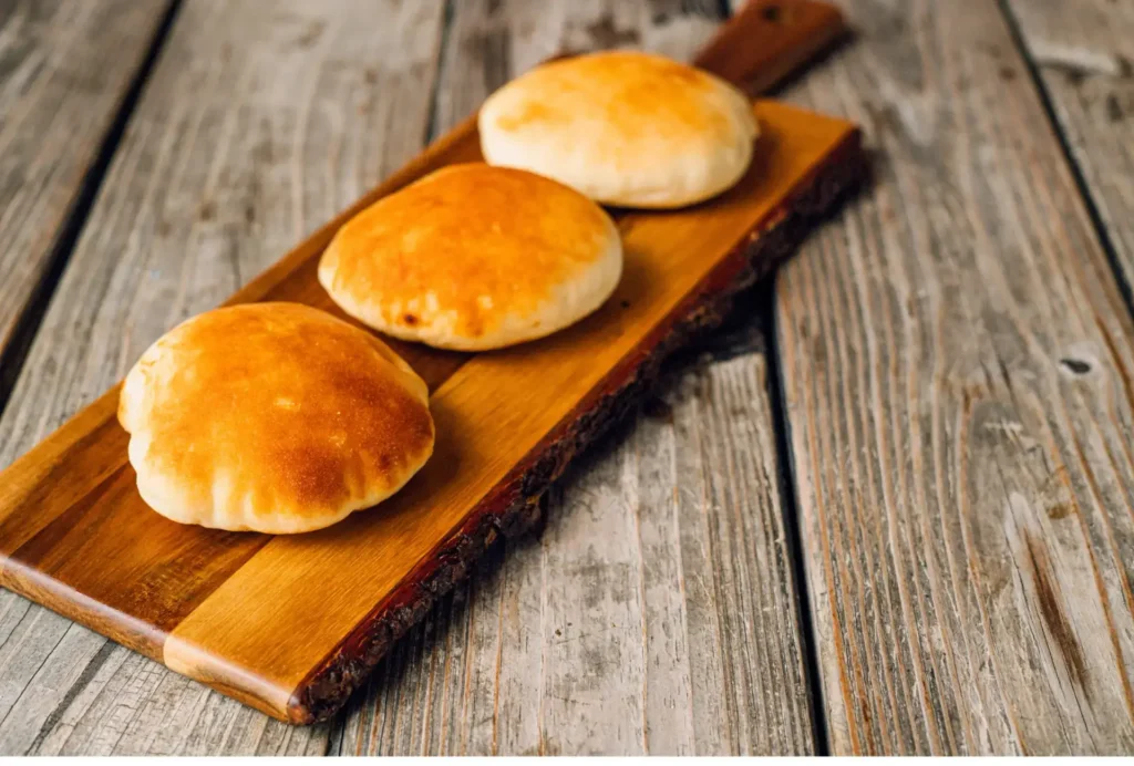 Fresh puffy brick oven pita, gloden brown which are displayed on a chopping block this is th eone and only Aladdins houston Perfect bread