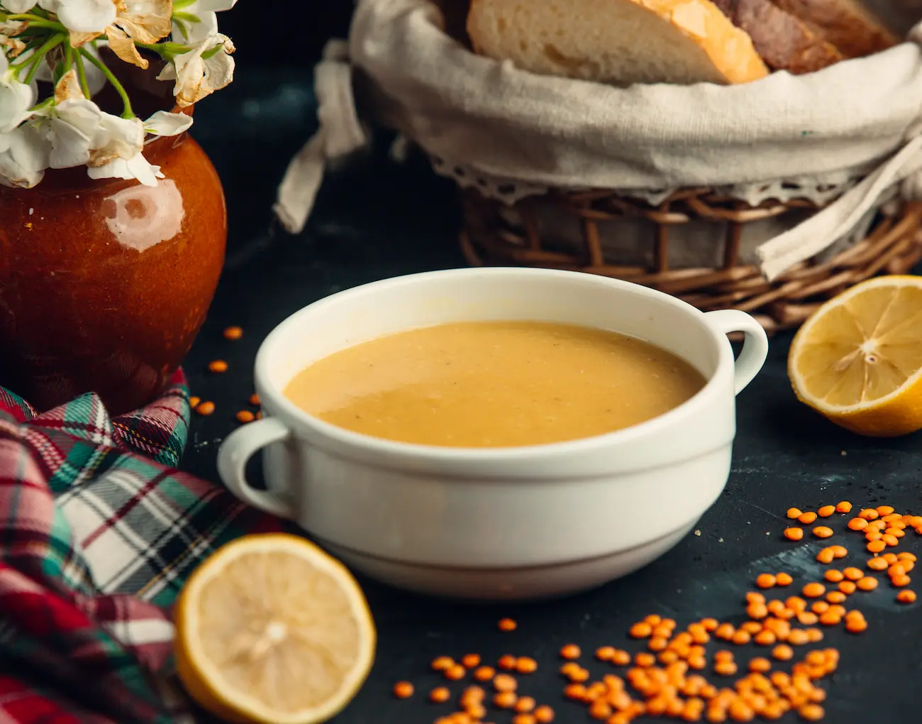 lentil soup served in white bowl with lemons