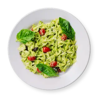 Bowtie pasta with basil pesto, cherry tomatoes, and sliced Kalamata olives, served in a white bowl.