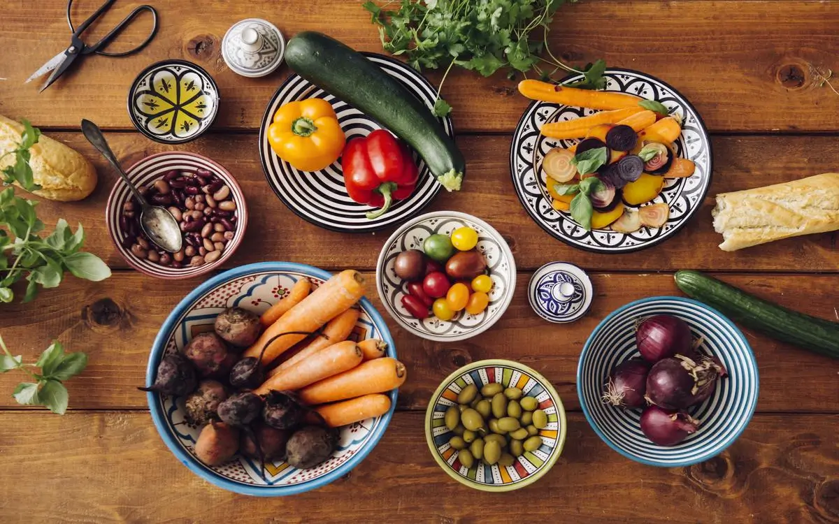 Fresh vegetables, olives, and whole foods arranged in colorful Mediterranean-style bowls.