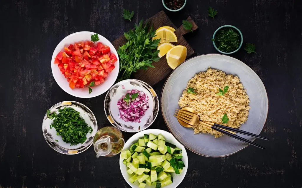 Fresh vegan tabouli salad with bulgur, parsley, tomatoes, and cucumbers, garnished with lemon wedges.