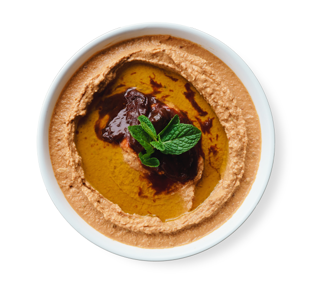 Spicy hummus topped with chili paste and olive oil, garnished with mint leaves, served at AladdinMediterranean Cuisine in Houston.