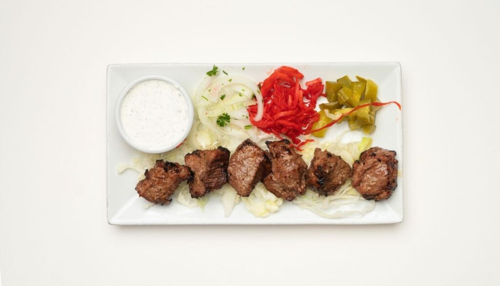 Grilled steak kabob plate with onions, pickled peppers, and tzatziki sauce from Aladdin Mediterranean Grill in Houston.