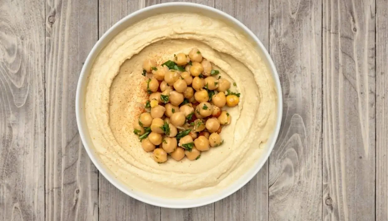 What is hummus — creamy chickpea and tahini dip served at Aladdin Mediterranean Cuisine in Houston, topped with olive oil and paprika.